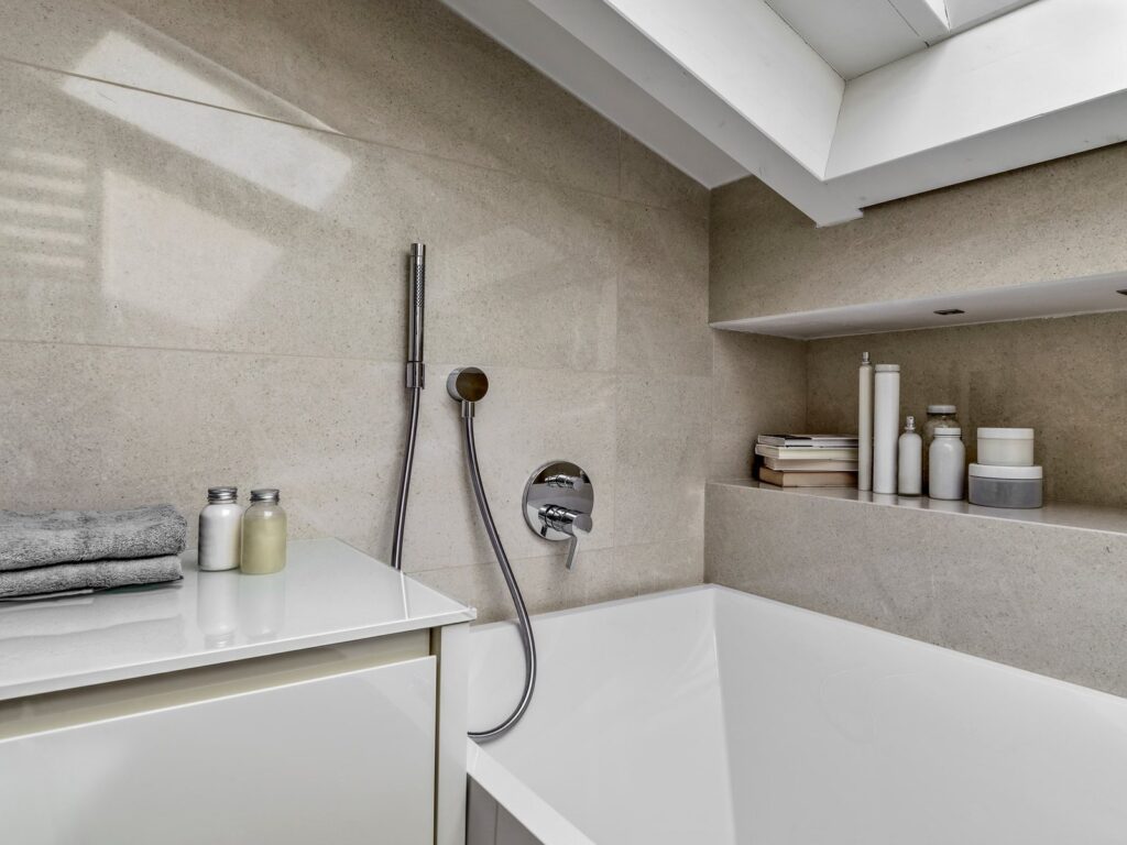 Détail d’une baignoire encastrée à Amiens avec carrelage effet pierre et robinet mural.