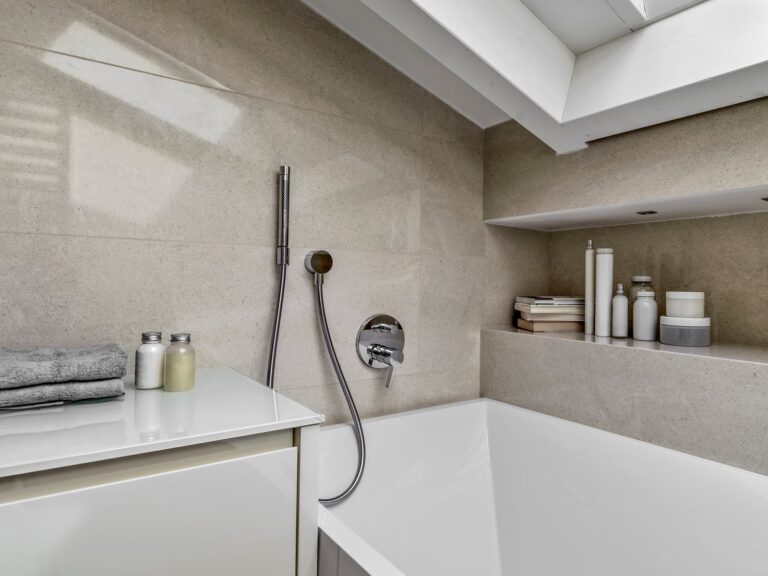 Détail d’une baignoire encastrée à Amiens avec carrelage effet pierre et robinet mural.
