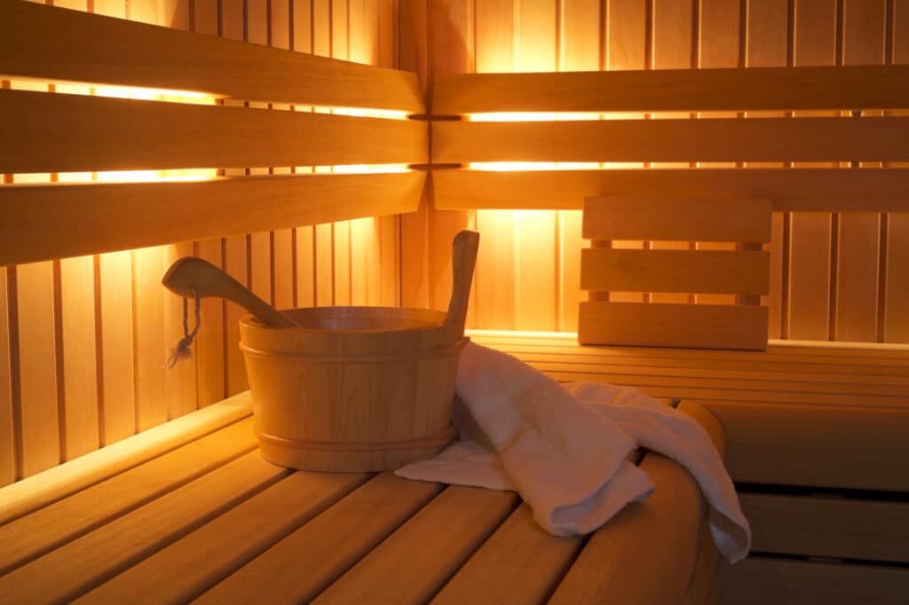 Intérieur de sauna en bois avec éclairage tamisé, seau et serviette - aménagement salle de bain à Amiens