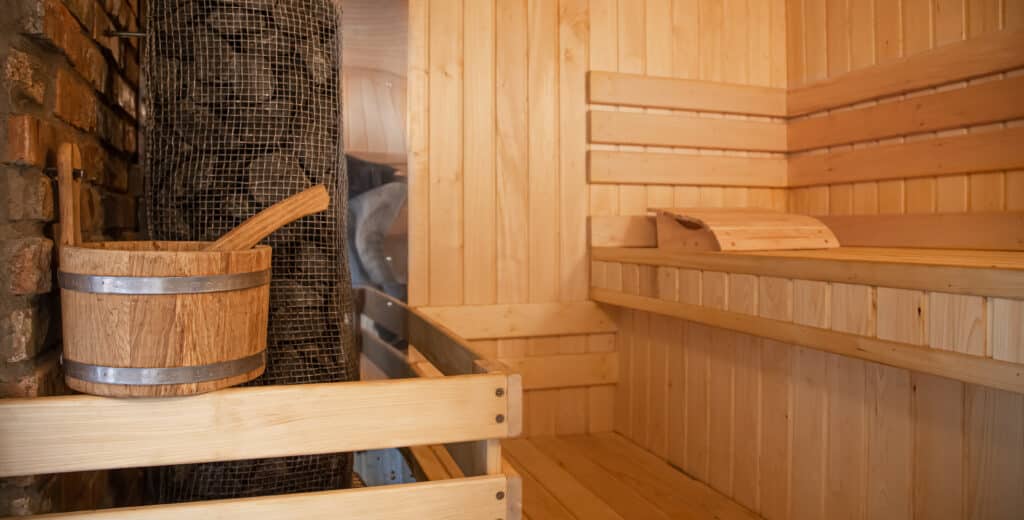 Sauna en bois avec poêle à pierres et seau traditionnel - aménagement salle de bain à Amiens par Lecomte Eric