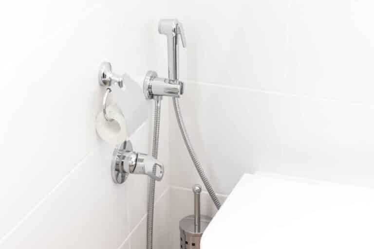 Mitigeur et douchette murale posés à côté d’un WC suspendu dans une salle de bain à Amiens.